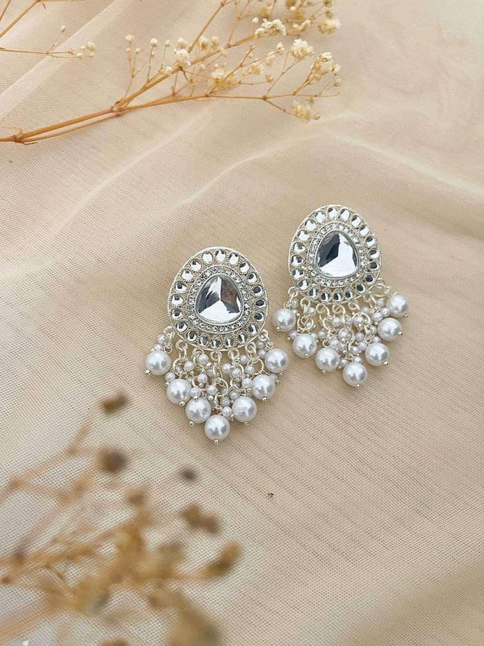 Beautiful silver earrings embellished with pearls on a soft fabric background.